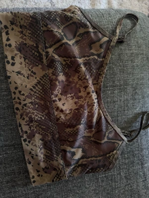 Brun sport-bh med ormmönster - Säljer en sport-bh från Aimn i brunt och beige med coolt ormmönster. Bh:n har smala axelband och är tillverkad i ett stretchigt material som passar perfekt för träning eller yoga.