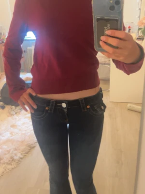Mörkröd stickad tröja - En enkel och stilren mörkröd stickad tröja med rund halsringning och långa ärmar. Tröjan har ribbade muddar vid ärmslut och nederkant. Perfekt att matcha med jeans eller kjol för en snygg look.