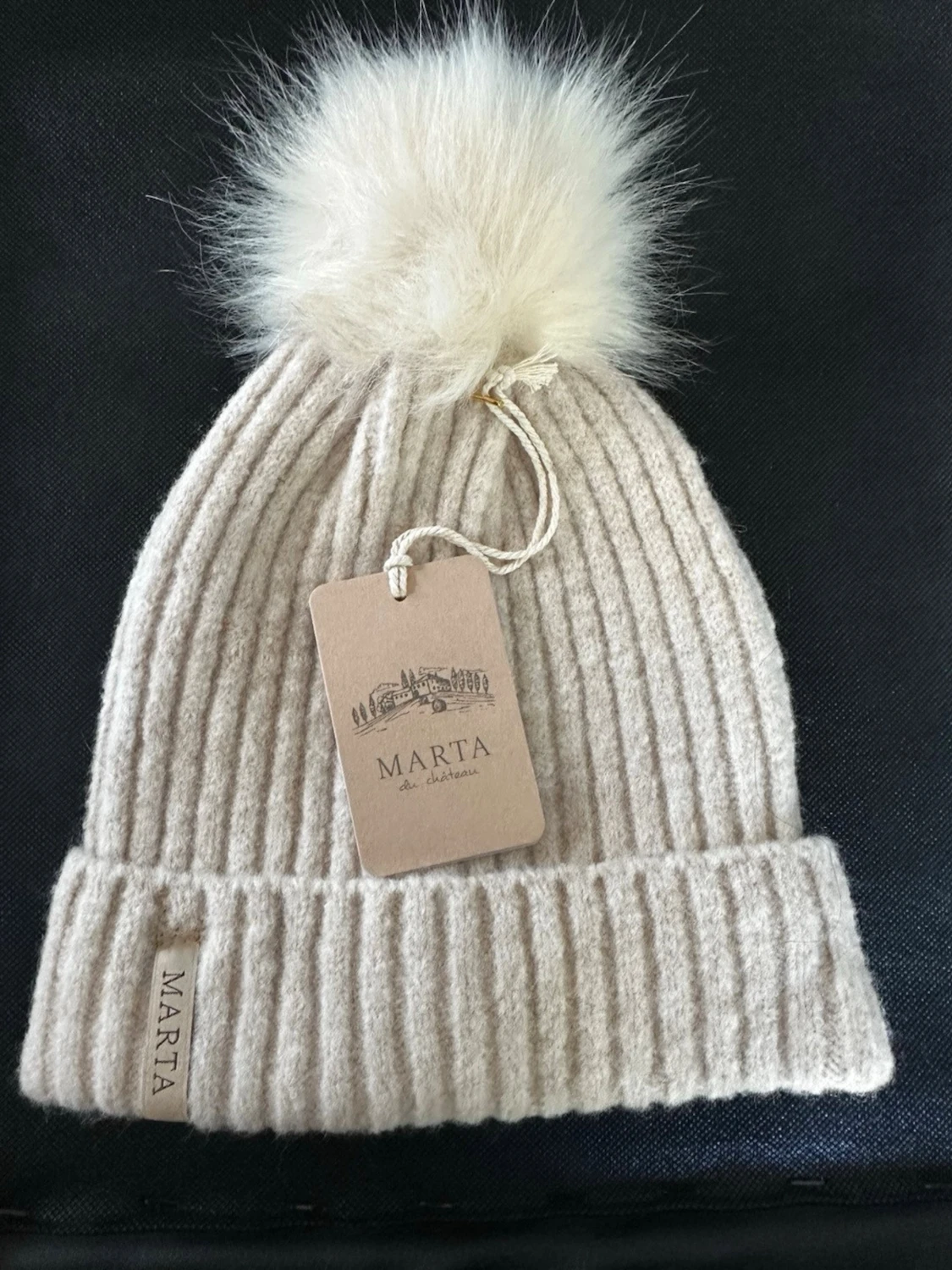 Beige ribbstickad mössa med pälsboll