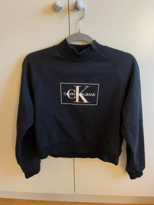 Svart sweatshirt🖤 - Snygg, stilren svart sweatshirt från Calvin Klein Jeans med lite högre krage och ribbade muddar. CK-märke fram i ljusrosa🤩🖤🩷