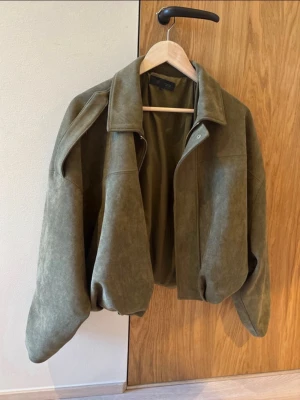 Zara mocka jacka grön - Snygg olivgrön skinnjacka med oversized passform och klassisk krage. Jackan har dragkedja framtill och breda ärmar för en avslappnad look. Perfekt för dig som vill ha en trendig och stilren jacka i garderoben.