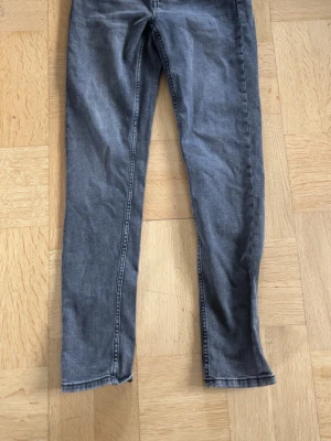 Gråa skinny jeans med smal passform - Säljer ett par gråa skinny jeans med smal passform och klassisk femficksdesign. Jeansen har en tvättad look och raka ben. Perfekta för dig som gillar en enkel och stilren stil. Materialet är denim med stretch för extra komfort.