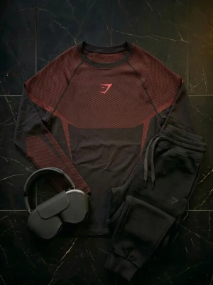  Onyx v5 långärmad träningströja från Gymshark - Snygg långärmad träningströja från Gymshark i svart och vinrött. Tröjan har ett sportigt mönster, rund halsringning och är tillverkad i en mix av nylon, polyester och elastan för maximal komfort och rörelsefrihet. Perfekt för gymmet eller löprundan. Sällsynt och eftertraktad då dessa inte säljs längre. Helt oanvänd vilket är ovanligt att hitta. Kopplas till ikoner som David Laid, Sam Sulek och andra Gymshark Atleter.