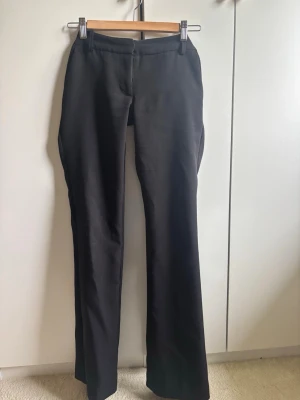 Svarta kostymbyxor från Bikbok - Snygga svarta kostymbyxor i flared-modell och pressveck. Byxorna har hällor för skärp och två bakfickor. Klassisk och stilren modell i ett mjukt tyg och två fickor framtill. Lite nopprigt vid benen från användning men inget som stör. Är i modellen Vera från Bikbok