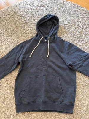 Mörkblå hoodie med vita snören - Snygg mörkblå  hoodie med klassisk känguruficka och vita dragsnören i huvan. Hoodien är en klassiker och passar till allt. Har använt den max 5 gånger 