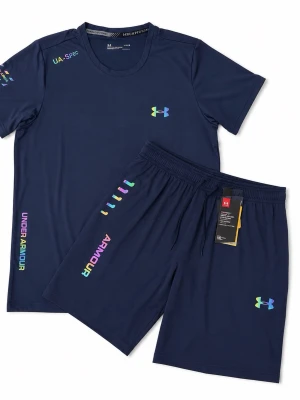 Marinblå träningsset från Under Armour - Snyggt marinblått träningsset från Under Armour med t-shirt och shorts. Setet har färgglada loggor och textdetaljer på både tröja och byxa. Tillverkat i ett lätt och snabbtorkande syntetmaterial, perfekt för träning och sportiga aktiviteter.