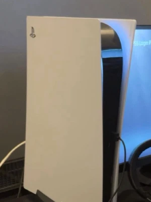 PlayStation 5 spelkonsol - Säljer en PlayStation 5 spelkonsol med futuristisk design i vitt och svart. Konsolen har en slimmad, stående form och är tillverkad i plast med blanka och matta ytor. Perfekt för gaming och underhållning.