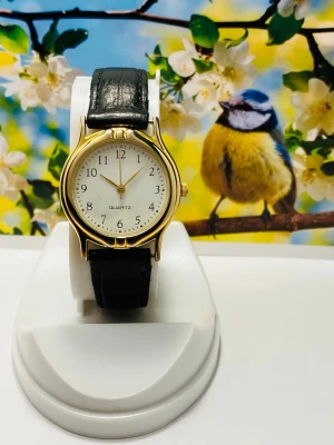 Klassisk guldfärgad Damklocka  - Klassisk Damklocka med rund vit urtavla, guldfärgat boett och tydliga svarta siffror. Svart äkta läder armband  ger en tidlös look. Perfekt accessoar för dig som gillar klassisk och enkel stil. 