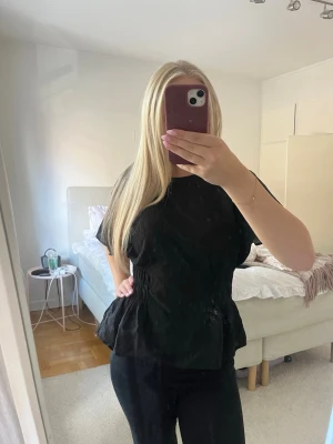 Svart blus med volang💓 - Säljer en svart blus med korta, lösa ärmar och volangdetalj nedtill. Inga defekter💓