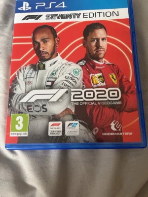 F1 2020 Seventy Edition PS4 spel - F1 2020 Seventy Edition till PlayStation 4 är ett racingspel där du kan tävla på ikoniska banor och skapa ditt eget team. Omslaget är rött och vitt med två förare i racingdräkter. Spelet levereras i ett blått plastfodral.
