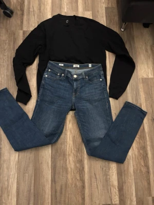 Blå jeans från Jack & Jones - Säljer ett par klassiska blå jeans från Jack & Jones. Jeansen har fem fickor, normal midja och raka ben. Snygga kontrastsömmar och patch med logga bak i midjan. Perfekta till vardagslooken och passar till det mesta med en svart hoddie 