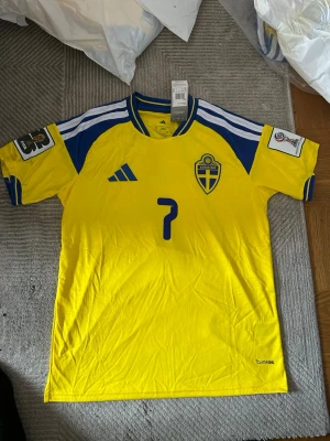 Svensk landslagströja  - Säljer en officiell svensk landslagströja från Adidas i storlek S. Tröjan är gul med blå detaljer, har nummer 7 på bröstet och Sveriges landslagsemblem. Tillverkad i lätt och funktionellt material med Climacool-teknologi och snygga ränder på axlarna.
