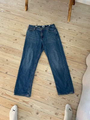 Blå raka jeans med fem fickor - Klassiska blå jeans med rak passform och fem fickor. Jeansen har normal midja och är tillverkade i ett slitstarkt denimtyg. Perfekta för en avslappnad och tidlös stil. Justerbar midja
