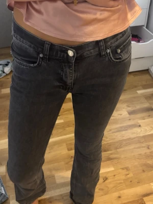 Mörkgråa jeans från gina tricot - Säljer ett par svarta bootcut jeans med låg midja och klassisk femficksdesign. Jeansen har en lätt tvättad look och raka ben som går ut lite nertill. Perfekta för en trendig och avslappnad stil.
