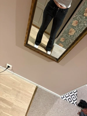 Svarta bootcut jeans med hög midja - Säljer ett par svarta bootcut jeans med hög midja och klassisk femficksdesign. Jeansen har en smal passform över låren och lätt utsvängda ben. Perfekta för dig som gillar en tidlös och trendig look.
