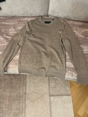 Beige stickad tröja i ullmix - Snygg beige stickad tröja med rund halsringning och långa ärmar. Tröjan har en klassisk passform och är tillverkad i en mjuk ullmix som känns skön mot huden. Perfekt för lager-på-lager och enkel att matcha med jeans eller chinos.