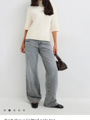 Vit stickad polotröja med kort ärm - Säljer en stilren vit stickad polotröja med korta ärmar och ribbade detaljer vid hals, ärmslut och nederkant. Tröjan har en hög polokrage och rak passform, perfekt att matcha med jeans eller kjol. Materialet ser mjukt och bekvämt ut. Helt ny med prislappen kvar aldrig använd säljer pga den var för liten för mig. Helt slutsåld på hemsidan❤️