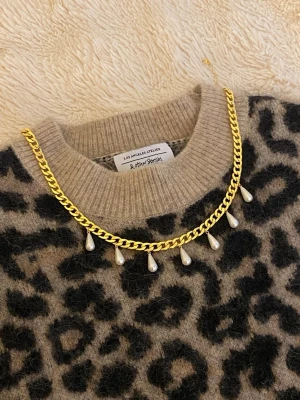 Guldhalsband med droppformade pärlor - Snyggt halsband i guldfärgad rostfritt med droppformade pärlor som hänger längs kedjan. Perfekt för att ge en trendig touch till din outfit. Kedjan har en klassisk design och pärlorna ger en elegant kontrast.