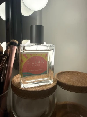 Clean Classic Tropical Escape parfym - Fräsch parfym från Clean Classic i doften Tropical Escape. Flaskan är fyrkantig i genomskinligt glas med en färgglad etikett i rosa, gult och blått samt svart lock. Perfekt för dig som gillar tropiska och lätta dofter. Använd fåtal gånger 