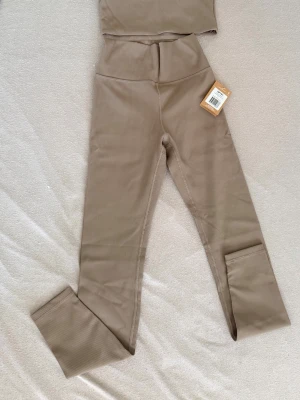 Beige ribbade set från aimn - Snygga beige leggings med ribbad struktur och hög midja. De har en tight passform och är perfekta för en trendig och bekväm look. Materialet är stretchigt och mjukt, vilket gör dem sköna att bära hela dagen.