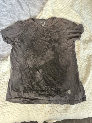 Grå t-shirt med tryck - Säljer en grå t-shirt med coolt mörkt tryck framtill och texten 'DON'T JUDGE ME' längst ner. T-shirten har rund hals och korta ärmar. Materialet känns som bomull och passformen är loose för en avslappnad vibe.