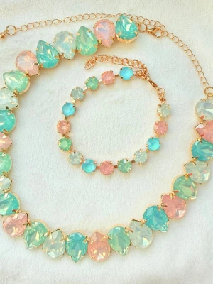 Pastellfärgat smyckeset  - Säljer ett smyckeset med halsband och armband i guldtonad metall. Båda har stenar  i pastellfärger som Aqua, mintgrönt, rosa och vitt. Kristallerna är droppformade och runda, vilket ger en unik och färgglad look. Reglerbar kedja på båda. 