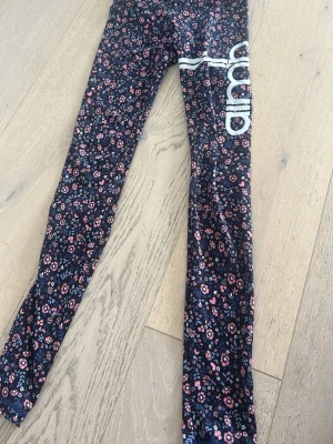 Mörkblommiga leggings med tryck - Snygga leggings med mörkblå botten och småblommigt mönster i rosa, vitt och blått. Storlek 146/150 men dom är väldigt stretchiga. (Passar som xxs/xs)