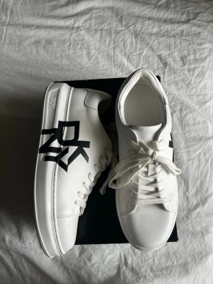 Vita DKNY sneakers med svart logga - Säljer dessa vita sneakers från DKNY. I princip nyskick endast testade, i storlek 40 med hög sula. Nypris 2199kr🤗