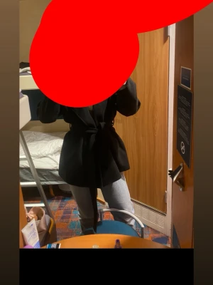 Svart kappa med knytskärp - Stilren svart kappa med knytskärp i midjan och klassisk krage. Modellen är rak och har fickor på sidorna. Perfekt för dig som vill ha en enkel men snygg look till vardags. Passar bra till jeans eller andra byxor.