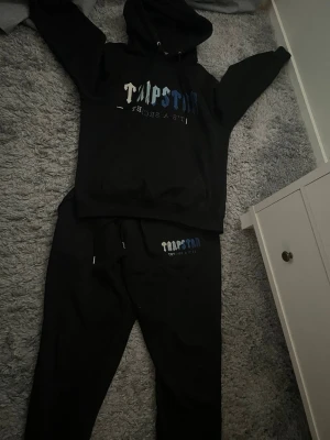 TRAPSTAR SET/TRACKSUIT - Säljer ett set från Trapstar med logga i vitt och blått på ena benet. Byxorna har dragsko i midjan och är gjorda i mjukt material som passar perfekt för chill dagar. Matchar snyggt med hoodie eller t-shirt.