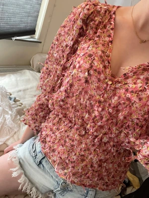  rosa blommig volangblus/Letnia koszulka  - Supersöt blus i tunn, luftig kvalitet med rosa botten och småblommigt mönster i vitt, gult och grönt. Blusen har volangdetaljer, v-ringning och trekvartsärmar. Mycket bra skick, tröjan är från zara och i storlek S