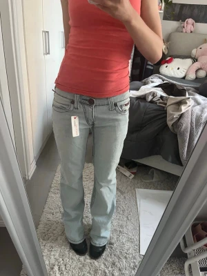 2000s jeans - Säljer ett par ljusblå bootcut jeans som är helt nya. Jeansen har låg midja och klassisk femficksdesign. Perfekta för dig som gillar en avslappnad men trendig look.