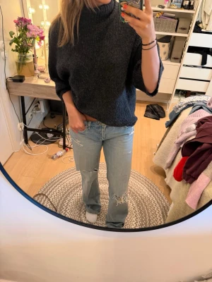 Mörkgrå stickad polotröja - Säljer en oversized mörkgrå stickad polotröja med trekvartsärmar och hög krage. Tröjan har en avslappnad passform och är perfekt för lager på lager. Materialet ser mjukt och mysigt ut, perfekt för kyligare dagar.