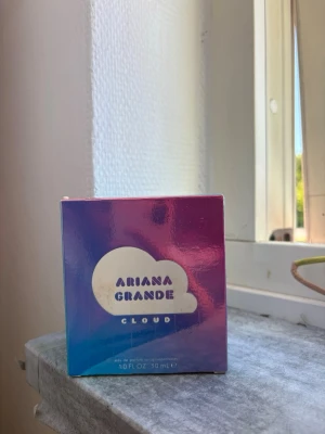 Ariana Grande Cloud parfym 30 ml - Ariana Grande Cloud parfym i en snygg holografisk box med blå, rosa och lila toner. Förpackningen har ett moln-motiv och rymmer 30 ml (1.0 FL OZ) eau de parfum. Perfekt för dig som gillar söta och fräscha dofter. Helt oanvänd ,plomberad dessutom. Nypris 440kr!