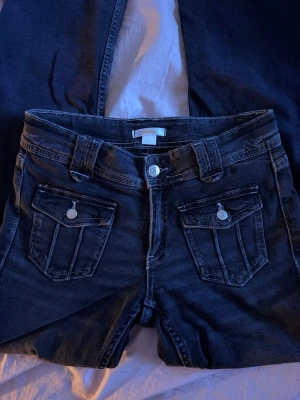 Mörkgråa jeans - Mörkgråa utsvängda jeans med fina fickdetaljer med medelhög midja. Knappt använda!