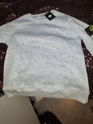 Grå sweatshirt från Stone Island - Stone Island Tröja – S/M – Helt ny 🩶  Säljer en grå Stone Island-tröja, helt ny och oanvänd. Storlek S, men passar även M beroende på hur man vill att den ska sitta.  ✅ Helt ny & oanvänd ✅ Storlek S ✅ Passar även M ✅ Grå 🔥 Clean och stilren modell  📦 Kan skickas eller mötas upp.  Pris: [699 ] kr