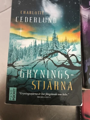 Gryningsstjärna & Midnattsljus och midddags mörker  - Två pocketböcker av Charlotte Cederlund: 'Gryningsstjärna' med ett färgstarkt omslag i blått, grönt och orange med vinterlandskap, och 'Midnattsljus' med lila och blå toner, skog och ett ansikte. Båda från Opal Pocket och har fantasifulla omslag.