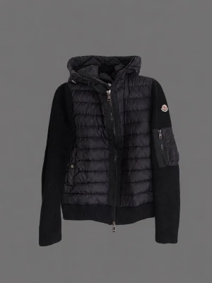 Svart cardiganjacka från Moncler - Snygg svart cardiganjacka från Moncler med quiltad front och huva. Ärmarna är stickade och har en ficka med dragkedja samt Moncler-logga på ena armen. Jackan har dragkedja framtill och ribbade muddar. Perfekt för lager på lager och streetstyle.