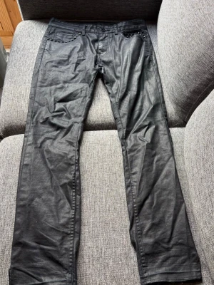 Svarta jeans med nitar - Säljer ett par svarta waxed jeans med coola nitar runt fickorna. Jeansen har rak passform och klassisk femficksdesign..