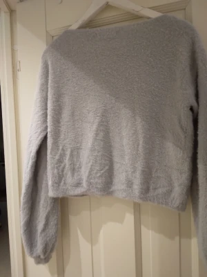 Ljusgrå / ljus blågrå fluffig jättemjuk stickad tröja, S-M - Mysig ljusgrå/ljus blågrå supermjuk och mysig stickad tröja med fluffig textur och avslappnad passform. Tröjan har långa ärmar och bred halsringning, perfekt för att hålla värmen under kyliga dagar. Strlk ca S-M. Felfri.