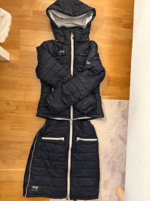 Svart vadderad jacka och kjol Uhip - Säljer ett marinblått vadderat set från Uhip med jacka och matchande kjol. 🤗 Storlek 150 i både jackan och ridkjolen. OBS! Säljes endast i sett, går ej att köpa separat 😊🥰