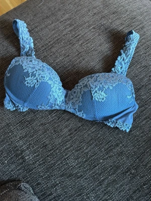 Intimissimi Gioia Pretty Flowers i en djupblå färg som inte finns längre - Snygg blå bh med vadderade kupor och vacker spetsdetalj över hela framsidan och axelbanden. Bh:n har justerbara band och hakknäppning bak. Perfekt för dig som gillar en feminin och stilren look.