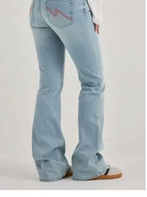 Ljusblå bootcut nelly  jeans - Säljer ett par helt oanvända nelly jeans ljusblå bootcut jeans med rosa zigzag-broderi på bakfickorna. Jeansen har hög midja och utsvängda ben, vilket ger en retro och avslappnad vibe. Perfekta för dig som gillar en trendig och bekväm stil.