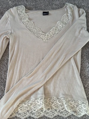 långärmad topp med spets Gina Tricot - Supersöt långärmad topp från Gina Tricot med v-ringning och spetsdetaljer vid halsringning och nederkant. Ribbad struktur som ger en snygg passform och romantisk vibe. 