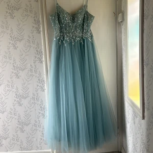 Balklänning  - En ljusblå balklänning i storlek L. Har snörning i ryggen så det går att anpassa storleken. Jag är 160cm lång och hade klackar till klänningen.