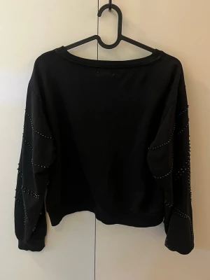 Svart sweatshirt med pärldetaljer - Kortare svart sweatshirt med pärldetaljer, vissa har försvunnit men inget som syns särskilt mycket. Skriv vid frågor💞