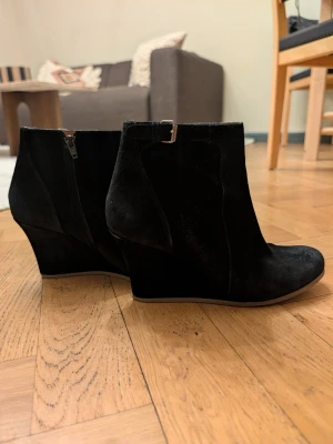 Lanvin svarta kilklackade stövletter i mocka 38 - Snygga svarta stövletter med kilklack och dragkedja på sidan. Tillverkade i mjuk mocka med en stilren design och rundad tå. Perfekta för dig som vill ha både höjd och komfort. Passar till många olika outfits och ger en cool vibe. Från lyxmärket Lanvin, dyra i inköp. 