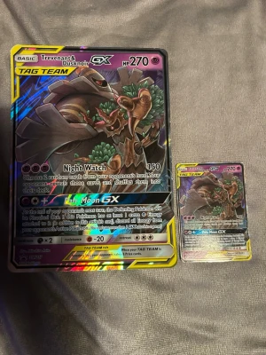 Pokémonkort Trevenant & Dusknoir GX jumbo - Säljer ett Pokémonkort av modellen Trevenant & Dusknoir GX i både jumboformat och standardstorlek. Korten har färgstark holografisk design med motiv av de två Pokémon och TAG TEAM-märkning. Perfekt för samlare eller som cool dekoration.