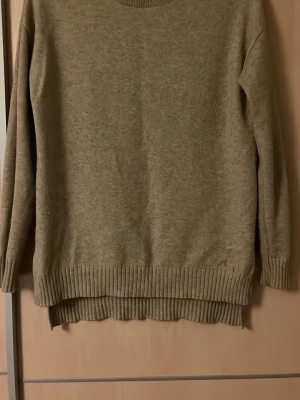 Beige stickad tröja från VILA - Mysig beige stickad tröja från VILA med rund halsringning och ribbade muddar vid ärmslut och nederkant. Tröjan har en enkel och stilren design, perfekt för lager på lager och passar till det mesta. Materialet känns mjukt och bekvämt.