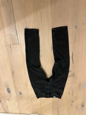 Svarta raka jeans - Säljer ett par svarta jeans med rak passform och klassisk femficksdesign. Jeansen har hög midja och är tillverkade i ett kraftigare denimtyg. Perfekta för dig som gillar en enkel och stilren look.